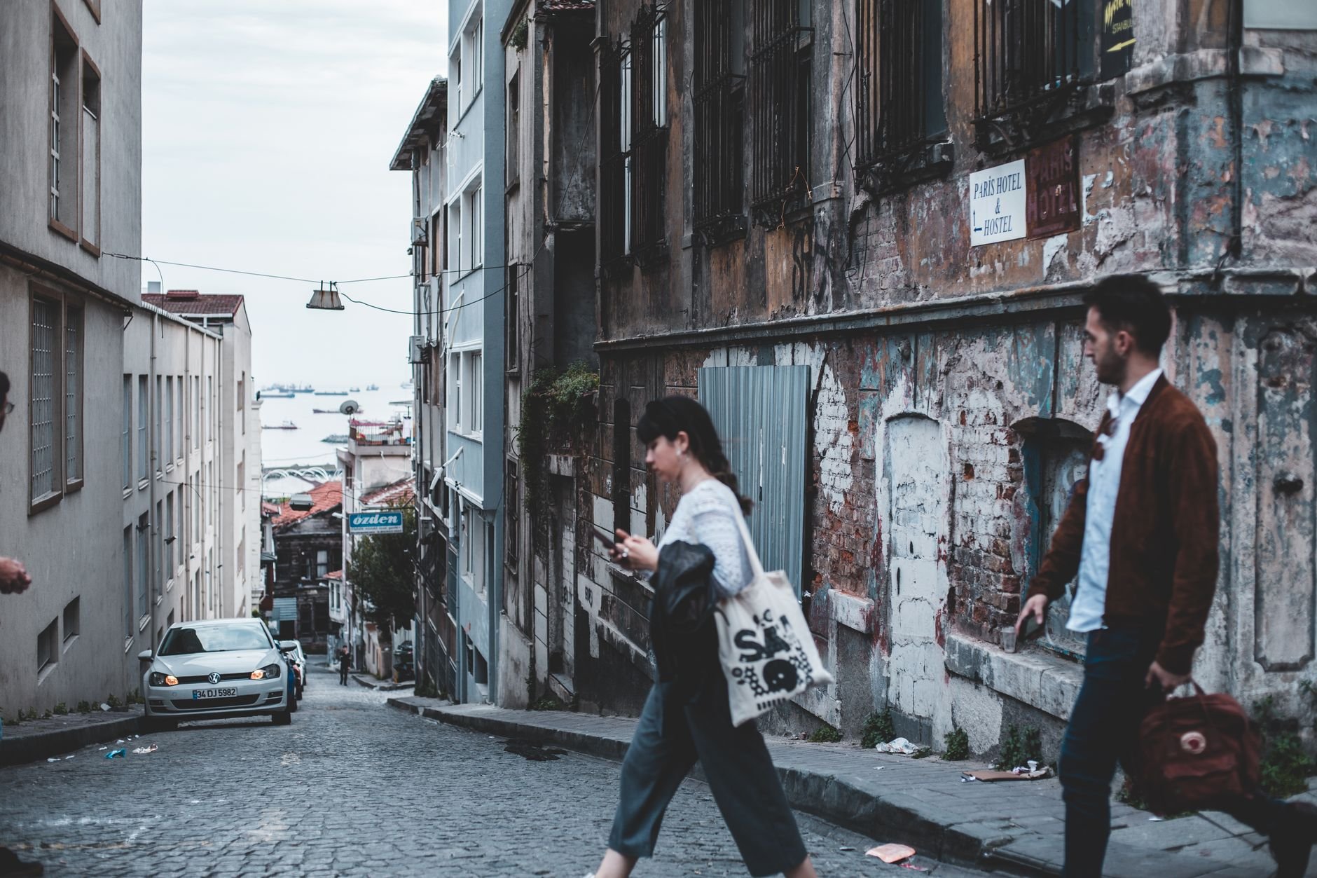 Candid street photo of people walking in an old city alley with rustic architecture.